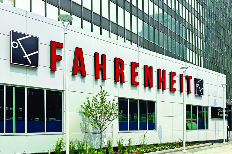 The striking red "Fahrenheit Cleveland" sign stands out against the modern white exterior of the restaurant in downtown Cleveland.