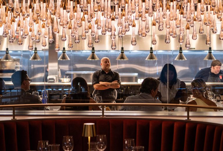 Guests enjoy dinner at Fahrenheit Cleveland, an upscale restaurant with an open kitchen and elegant teardrop chandeliers in Cleveland.