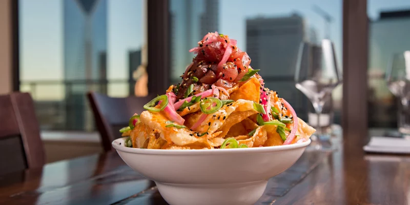 A bowl of Ahi Tuna Nachos at Fahrenheit Charlotte, with crispy wonton chips, fresh tuna, pickled onions, and sliced jalapeños.
